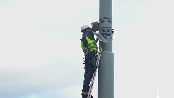 Municipal Engineer Standing on Ladder at Height, Hazardous Maintenance Work alt