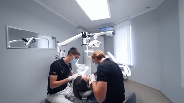 Dentist at work with patient. Woman sits in dentist chair while dentist examine her teeth alt