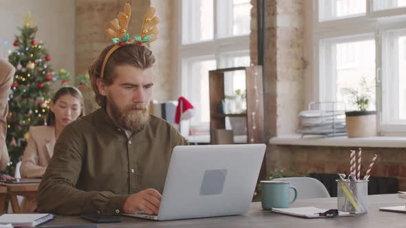Businessman Checking Messages on Phone in Office on Christmas alt