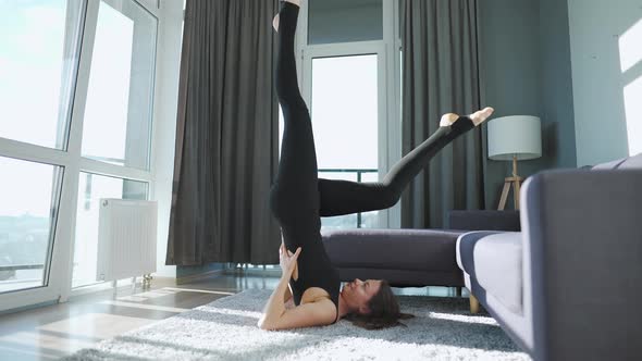 Young Caucasian Woman in Black Jumpsuit Doing Yoga at Home To Develop Flexibility and Balance alt