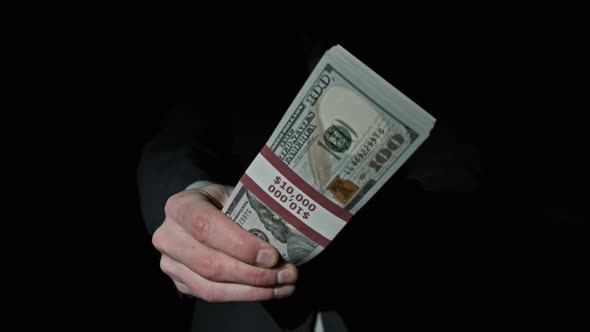 Stack of 10000 American Dollars in Bundle in Male Hands on Black Background alt