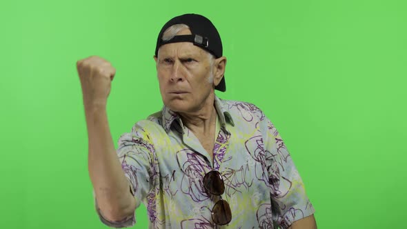 Senior Man Tourist Quarrels at Someone Threateningly Moves with His Hands Fist alt
