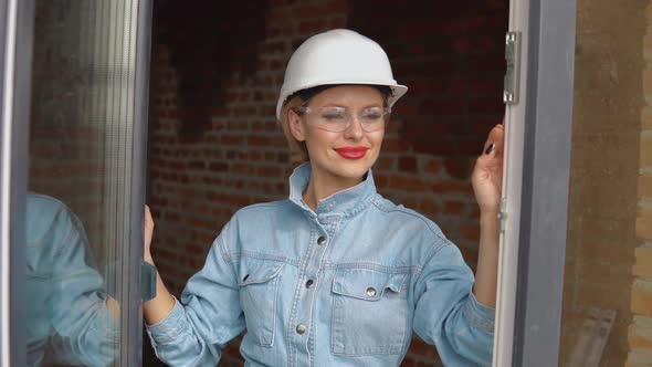 A Female Architect or Bricklayer Stands in an Open Window at a Construction Site alt
