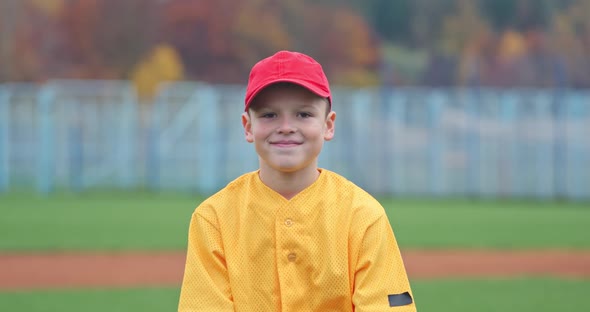 Portrait of a Boy Baseball Player on a Blurry Background the Pitcher Holds the Ball in His Glove and alt