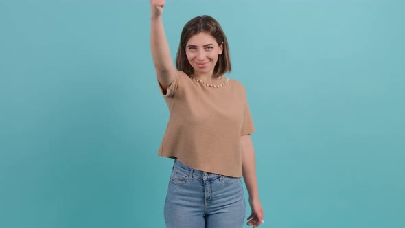 Happy Woman Showing Thumbs Up Gesture Isolated Over a Turquoise Background alt