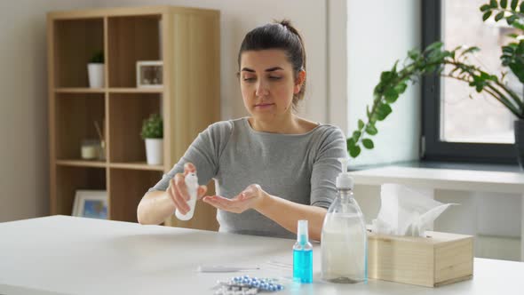 Woman Spraying Hand Sanitizer at Home alt