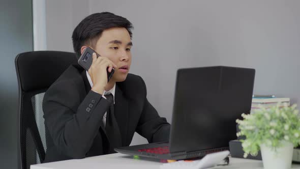 young business man talking on mobile phone and using laptop alt