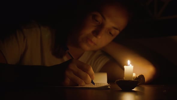 Closeup of Young Woman is Writing By Pen in Candlelight at Darken Room