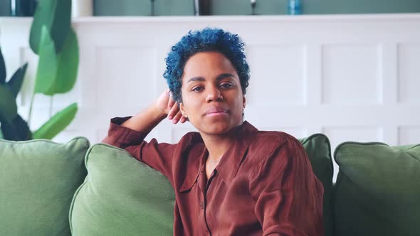 Young Laughing African American Woman Points Remote at Screen and Turns on TV alt