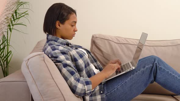 American Woman in Casual Clothes Working at Home Online Lying on the Couch