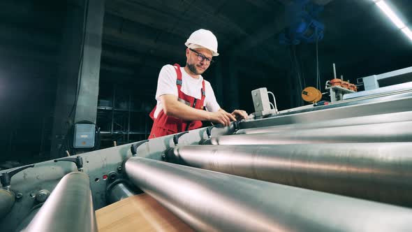 Metallurgy Worker Is Adjusting the Rolling Conveyor alt