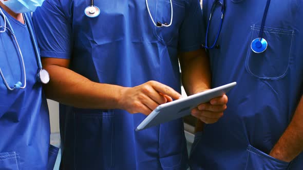 Male and female surgeons discussing over digital tablet in operation room alt