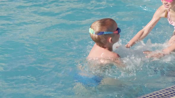 Little Boy and Girl Swimming in Swimming Pool Children Having Fun Splashing Water alt
