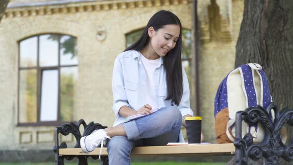 Happy Asian Student Woman Sitting on The Bench and Studying