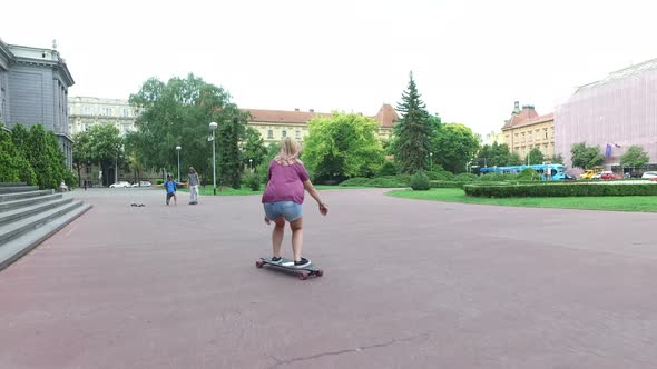 Woman on a longboard having fun with friends in the city alt