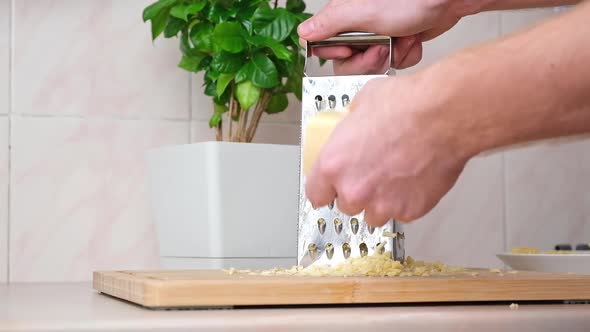 A Man Rubs Cheese on Metal Grater for Freezing and Further Cooking Pizza Pasta