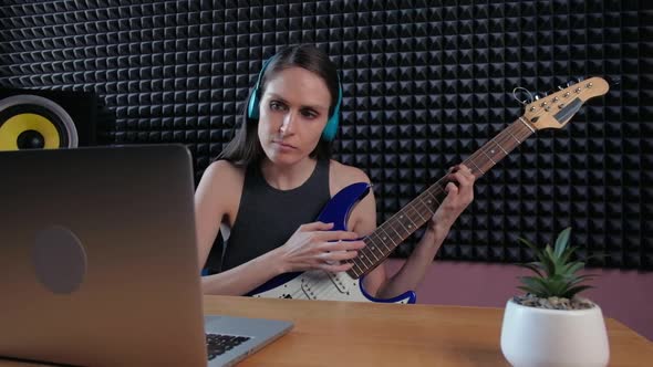 Female Learning Play Guitar at Home Using Online Lessons alt