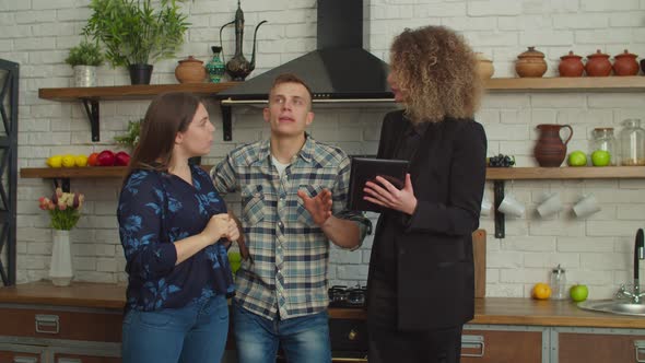 Lovely Female Interior Designer and Couple Discussing Future Design of House alt