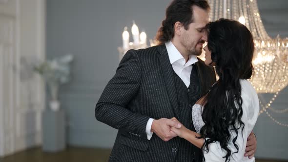 Man is Hugging Tenderly His Bride in Wedding Day Newlyweds are Posing in Luxury Hall alt