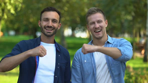 Male Friends Bumping Fists and Smiling on Camera Outdoors, True Friendship alt