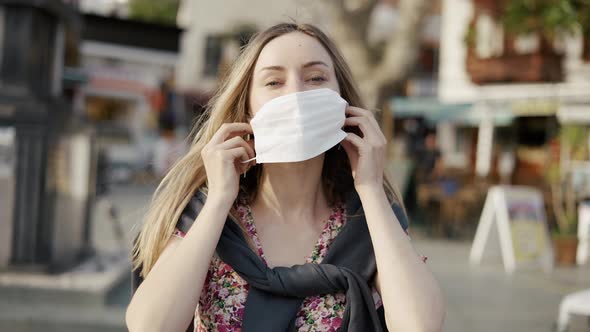 Blonde Woman Putting on Medical Mask on Crowdy Street alt