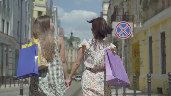 Back View of Two Walking Women with Shopping Bags alt
