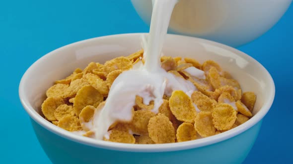 Milk pouring into bowl of corn flakes cereal