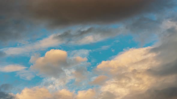 Golden Clouds and Dark Thunderclouds Floating Across Sunny Blue Sky. Time Lapse