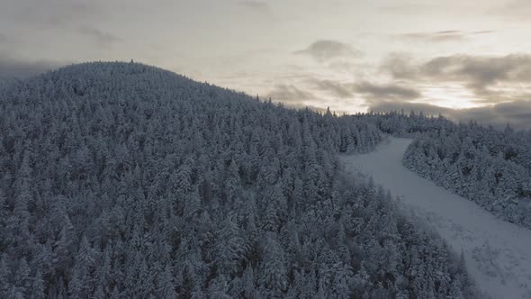 Abandonded ski trail at the peak of a snow covered mountain SLOW AERIAL ORBIT alt