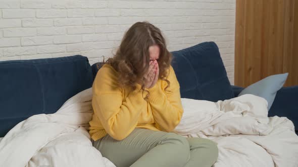 Woman in Sweater Sits on Bed and Coughs and Sneezes alt