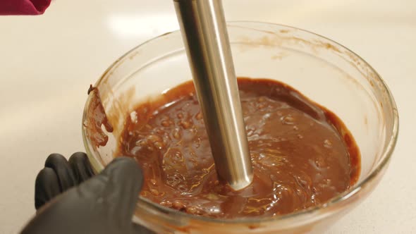 Close up gimbal shot of hands with mixer mixing chocolate alt