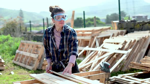 Woman turning over wooden boards in countryside alt