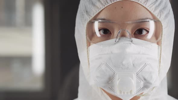 Asian Woman in Protective Mask and Glasses Looking at the Camera Chinese Coronavirus Quarantine Zone alt