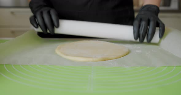 Close Up. Chef Hands in Black Gloves Preparing the Cake or Putting Pizza Dough on Board alt