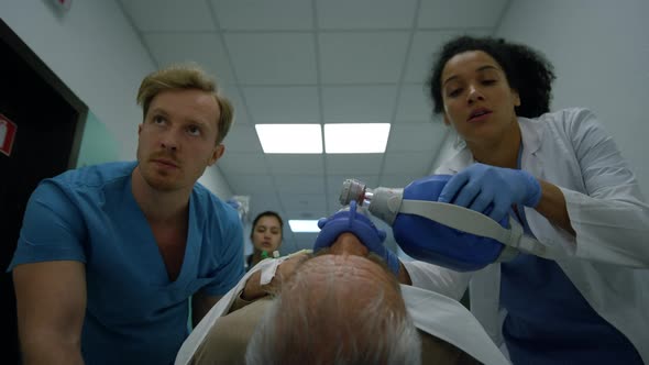 Worried Medical Group Pushing Patient on Gurney on Hospital Corridor Close Up alt