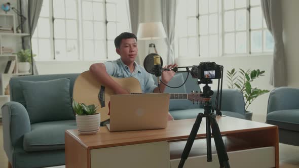 Asian Vlogger With Guitar Talking To Camera. The Boy Is Streaming For His Channel alt