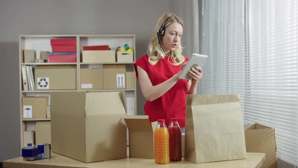 Warehouse Worker is Working in an Office Room Against Background of Boxes alt