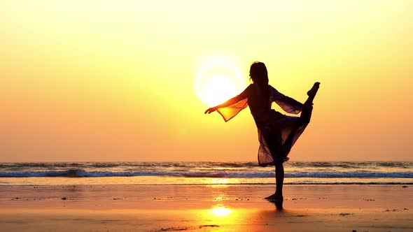 Silhouette of Young Woman Performing Rhythmic Gymnastics Element on the Beach