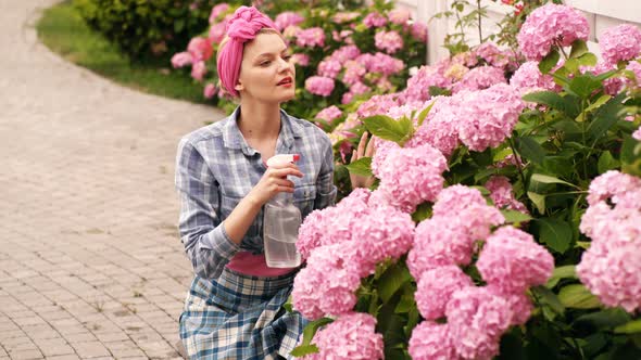 Woman Watered Flower in Her Yard in the Summer. Happy Girl Watering Hydrangeas. Concept of Care alt