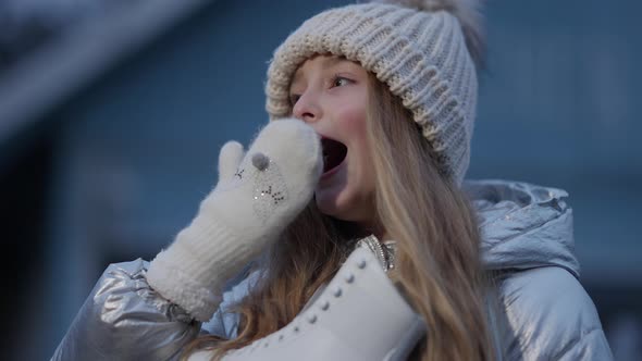 Beautiful Caucasian Little Girl Yawning and Smiling at Camera Standing on Ice Rink with Skates alt