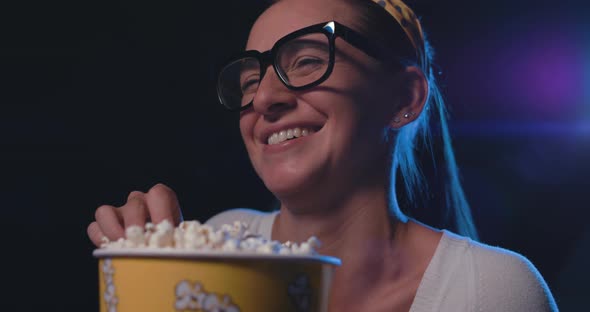 Woman watching a comedy movie at the cinema and eating popcorn