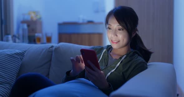 Woman use of smart phone sit on sofa at home in evening alt