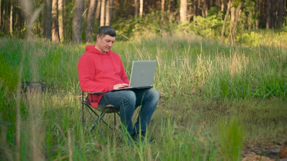Man Working on Laptop in Summer Forest alt