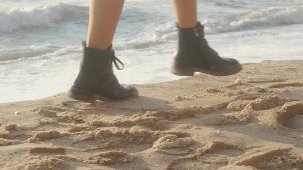 Closeup Cinematic Shot of Woman Feet in Boots Walking on the Beach at Sunset or Sunrise alt