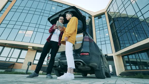 Courier Gives a Parcel To a Client Near the Car alt