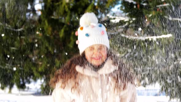 Happy Little Girl Throwing Snow in Winter Park alt