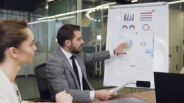 Business People Sitting at Boardroom Table and Listening the Explaination of Charts alt