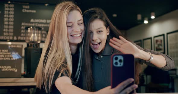 Attractive Young Women Making Video Call on a Mobile Phone Make in Cafe Chat alt