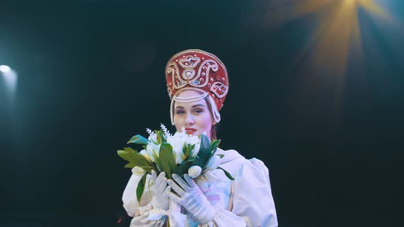 a theater actress with flowers in her hands in a bride's dress on stage. opera. performance.