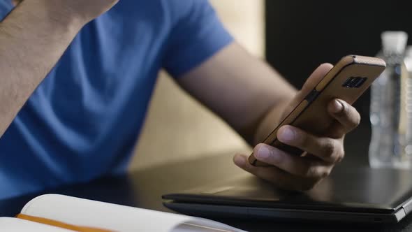 Close-up of Smartphone in Young Male Hand. Unrecognizable Middle Eastern Guy Eating Apple and alt